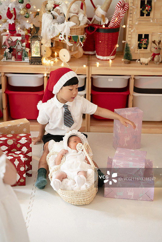 豪华圣诞屋里的幼儿小哥哥呵护摇篮里的女婴妹妹图片素材
