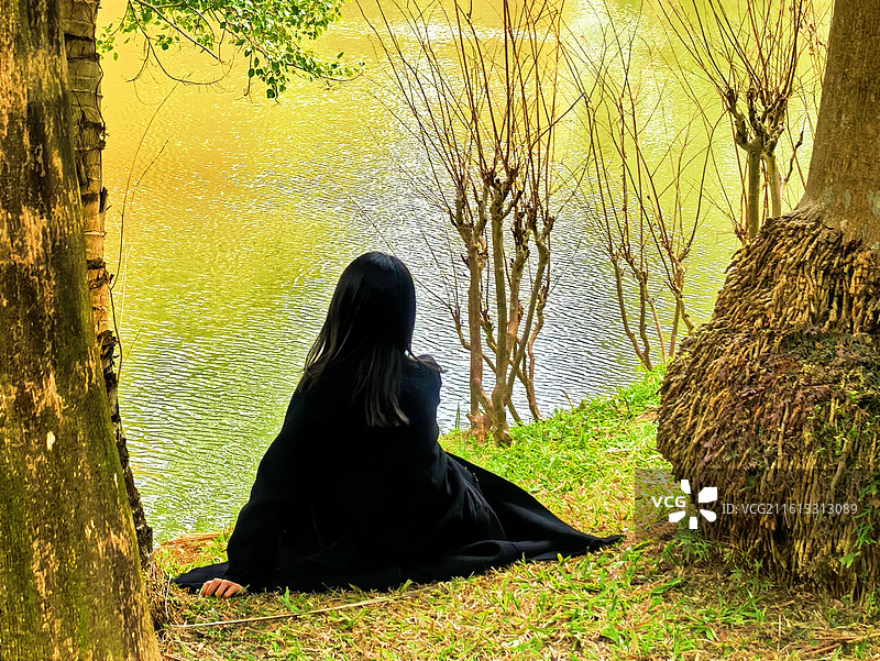 静坐湖畔 背影入画，黑衣融于树影。看粼粼波光，听风穿过枝桠。这一刻，安静得只剩下呼吸与自然的私语。图片素材