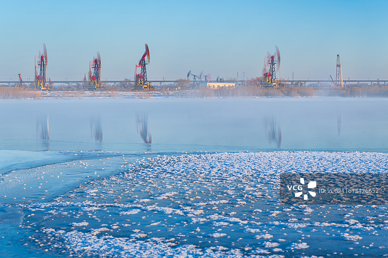 冬天的抽油机不知疲倦地上下摆动，曲柄在湿地中划出永恒的弧线。图片素材