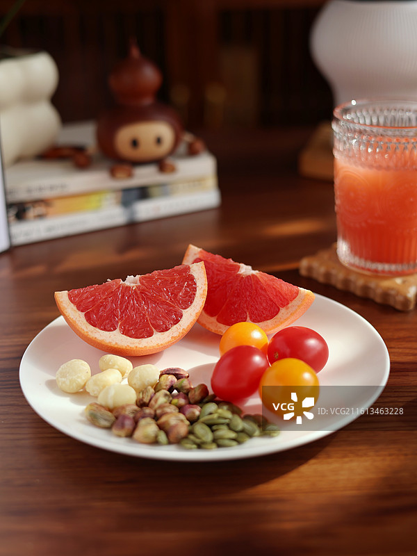 静物拍摄暗调白色碟子里有切开的西柚和水果及坚果图片素材