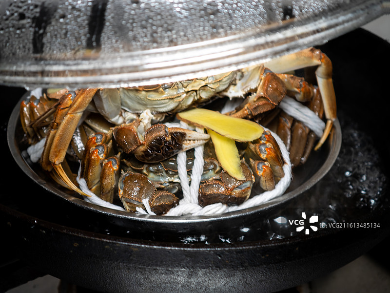 锅中正在隔水清蒸的鲜活大闸蟹与生姜片图片素材