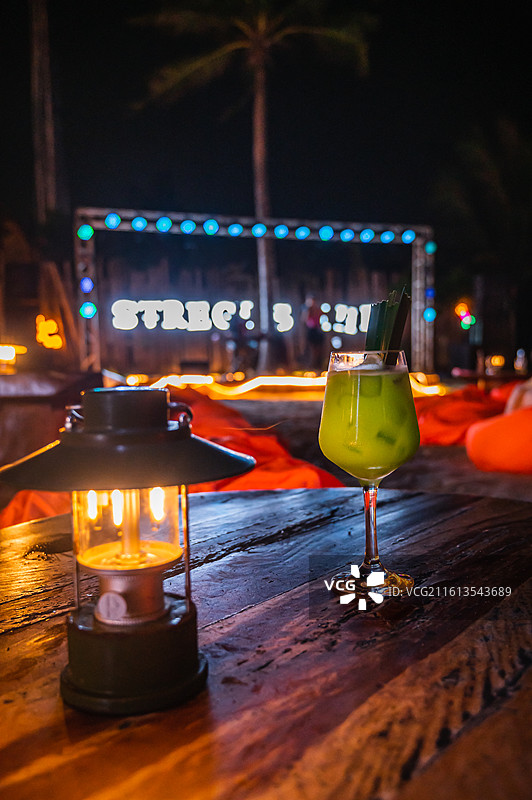 浪漫海滨之夜：沙滩吧台上的精致冷饮与明灯图片素材