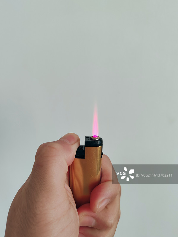 一只手点亮打火机，打火机红色的火焰图片素材