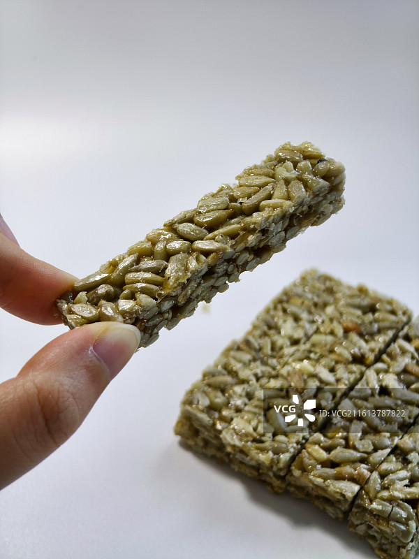 白色背景上手持食物的特写镜头 香脆瓜子酥 酥糖解馋零食坚果 国庆休闲户外年货追剧 坚果炒货小吃 葵花图片素材