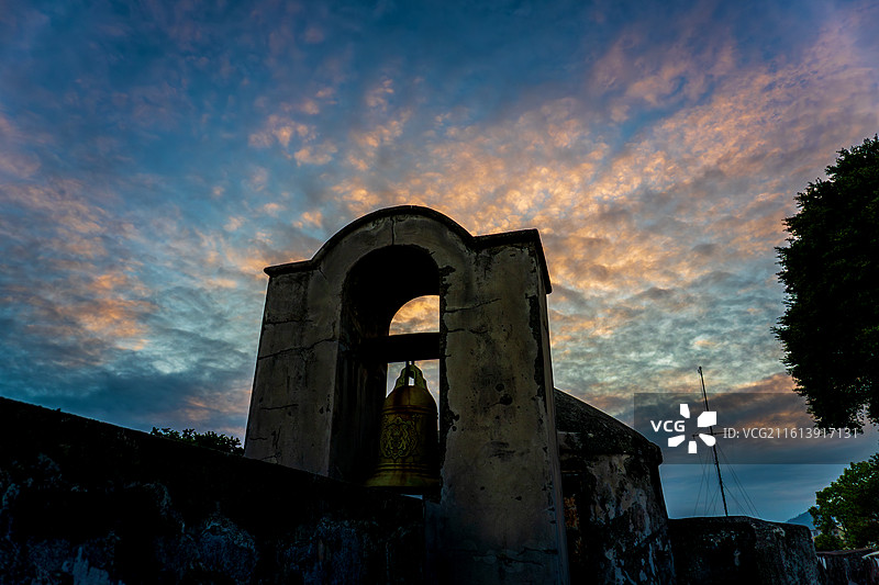 彩色晚霞下的澳门大炮台古老铜钟图片素材
