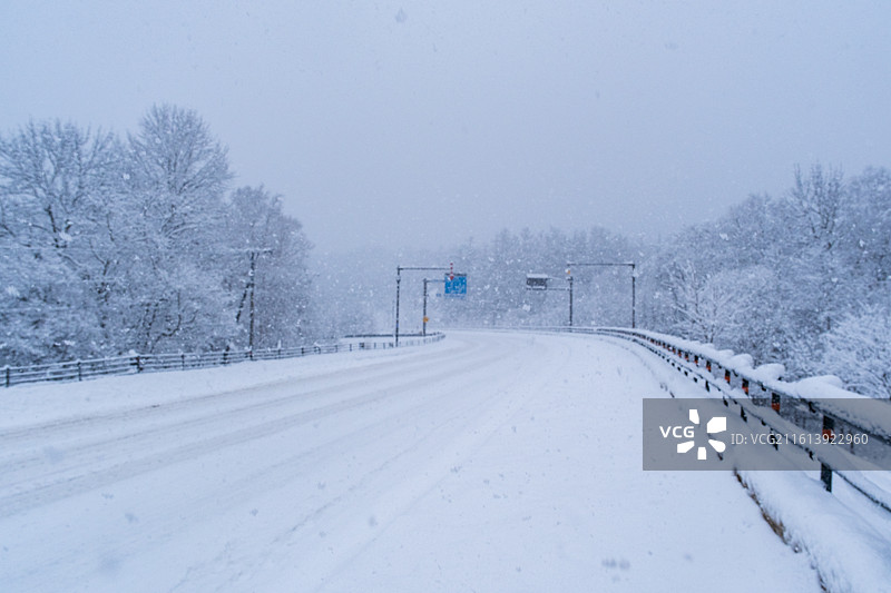 冬天日本北海道道东钏路市阿寒湖，雪景中的阿寒川日式豪华温泉旅馆酒店，大雪纷飞雪地上树木和空无一人街道图片素材