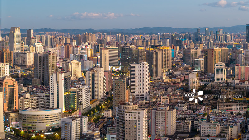 傍晚的昆明城市天际线航拍，落日余晖将城市染成金色。图片素材