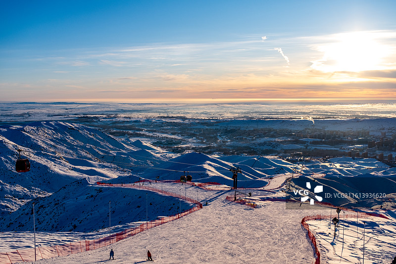 冬天新疆阿勒泰将军山滑雪场俯瞰冬季雪后雪山与城市景观的高角度俯瞰图，日落时白雪皑皑的群山景色图片素材