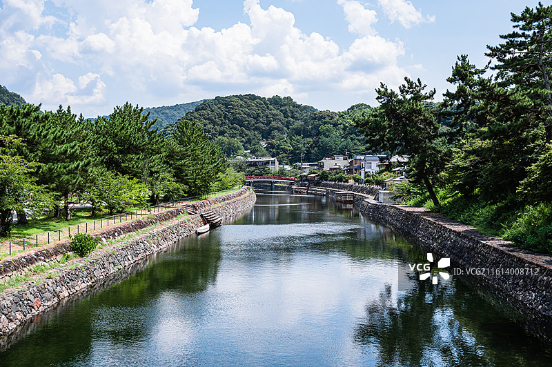 日本宇治川支流如镜的水面与远处的红色朝雾桥图片素材
