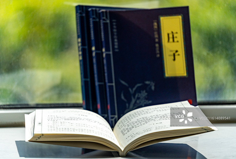 绿色虚化背景中窗台上摆放的庄子道德经道家学说书籍书本特写镜头图片素材