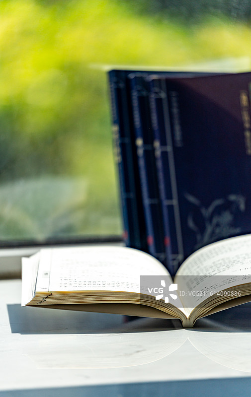 绿色虚化背景中窗台上摆放的庄子道德经道家学说书籍书本特写镜头图片素材