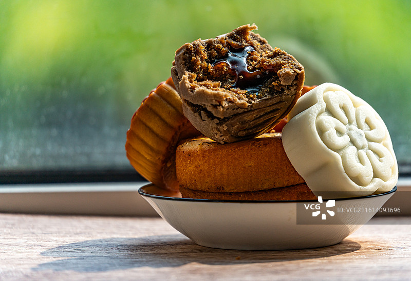 绿色虚化背景中的盘子里的中国中秋节传统美食小吃冰皮糕点月饼甜食特写镜头图片素材