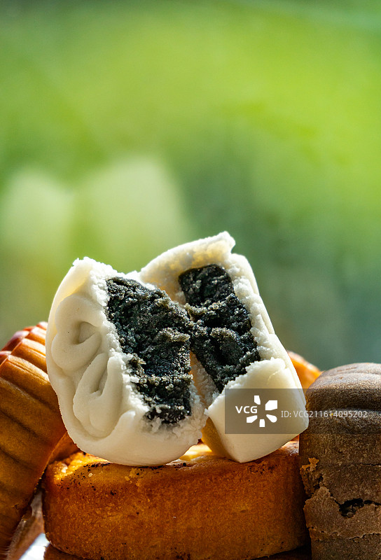绿色虚化背景中的盘子里的中国中秋节传统美食小吃冰皮糕点月饼甜食特写镜头图片素材