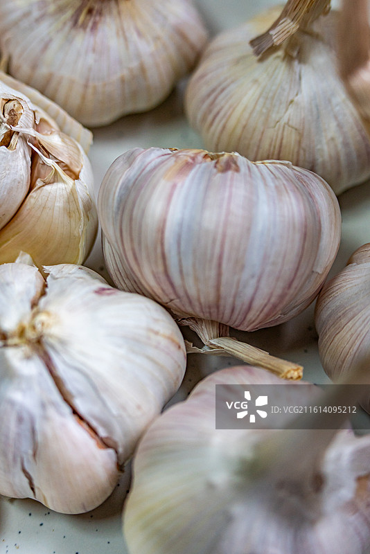 木桌上盘子里的新鲜大蒜蒜头紫皮蒜调味品食物的高角度视图.金乡大蒜苍山大蒜的区别图片素材