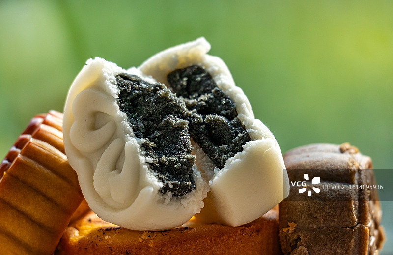 绿色虚化背景中的盘子里的中国中秋节传统美食小吃冰皮糕点月饼甜食特写镜头图片素材