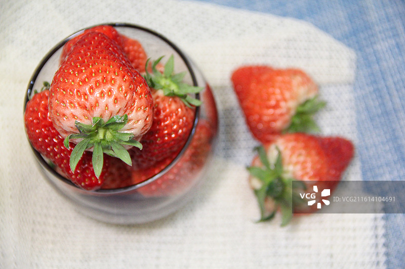 蓝色白色纱布上散乱的红色草莓特写图片素材