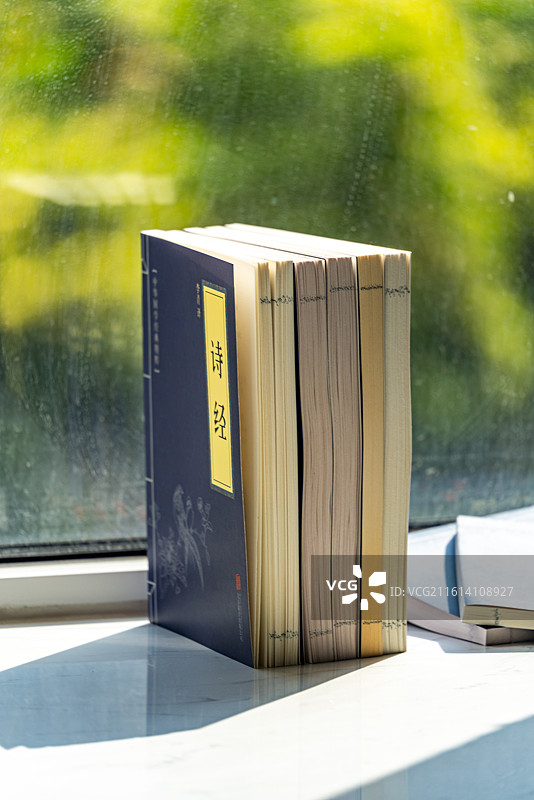 绿色虚化背景中窗台上摆放的四书五经国学书籍论语孟子大学中庸诗书礼易春秋书本特写镜头图片素材