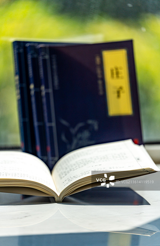 绿色虚化背景中窗台上摆放的庄子道德经道家学说书籍书本特写镜头图片素材