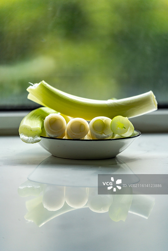 绿色虚化背景中盘子里的新鲜葱山东大葱章丘大葱葱白调味品食物的高角度视图图片素材