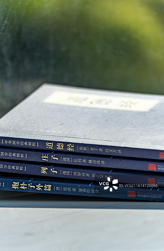 绿色虚化背景中窗台上摆放的庄子道德经道家学说书籍书本特写镜头图片素材