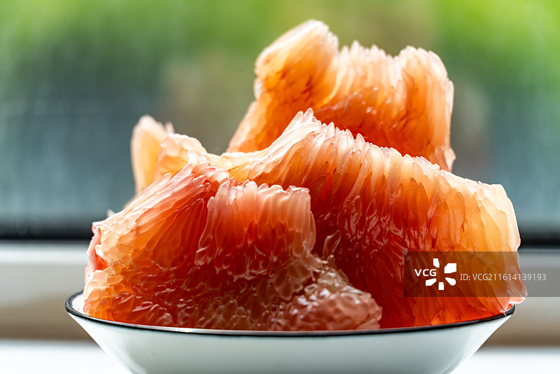 绿色虚化背景中桌子上盘子里的红柚蜜柚柚子水果果肉特写镜头图片素材