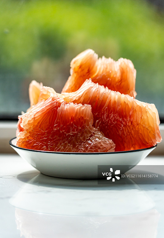 绿色虚化背景中桌子上盘子里的红柚蜜柚柚子水果果肉特写镜头图片素材