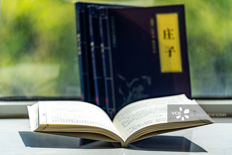 绿色虚化背景中窗台上摆放的庄子道德经道家学说书籍书本特写镜头图片素材