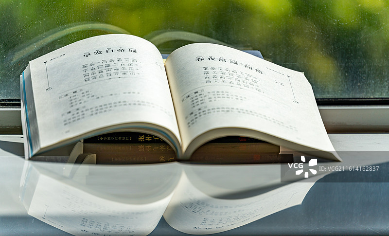 绿色虚化背景中窗台上摆放的唐诗三百首阅读书籍书本特写镜头图片素材
