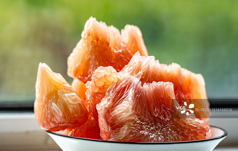 绿色虚化背景中桌子上盘子里的红柚蜜柚柚子水果果肉特写镜头图片素材