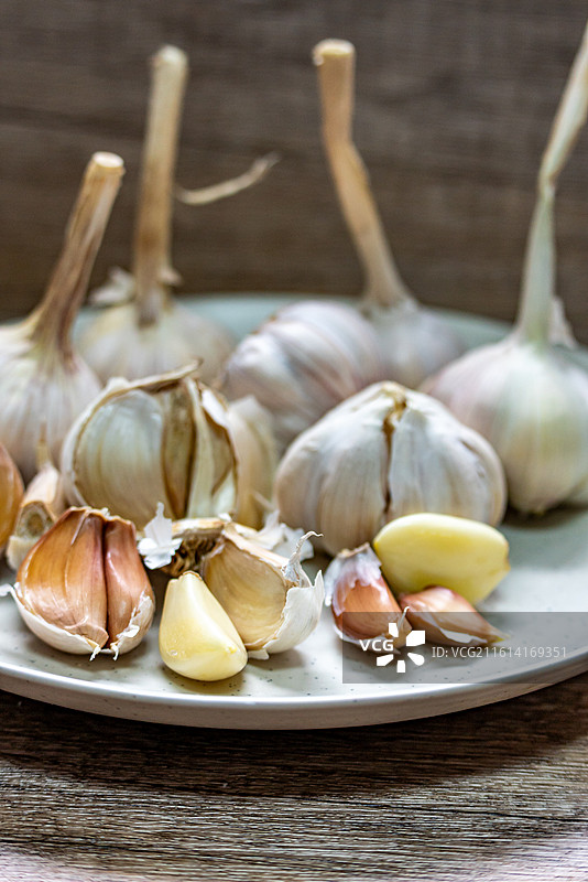 木桌上盘子里的新鲜大蒜蒜头紫皮蒜调味品食物的高角度视图.金乡大蒜苍山大蒜的区别图片素材