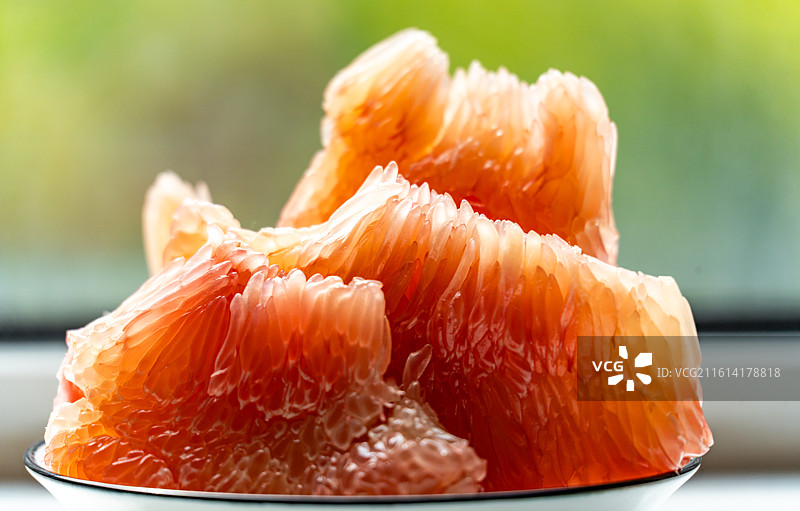 绿色虚化背景中桌子上盘子里的红柚蜜柚柚子水果果肉特写镜头图片素材