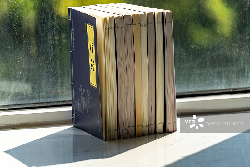 绿色虚化背景中窗台上摆放的四书五经国学书籍论语孟子大学中庸诗书礼易春秋书本特写镜头图片素材