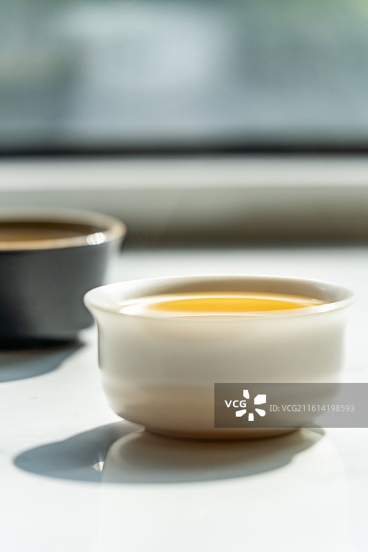 绿色虚化背景中窗户阳台上的茶杯茶具一杯清茶特写镜头图片素材