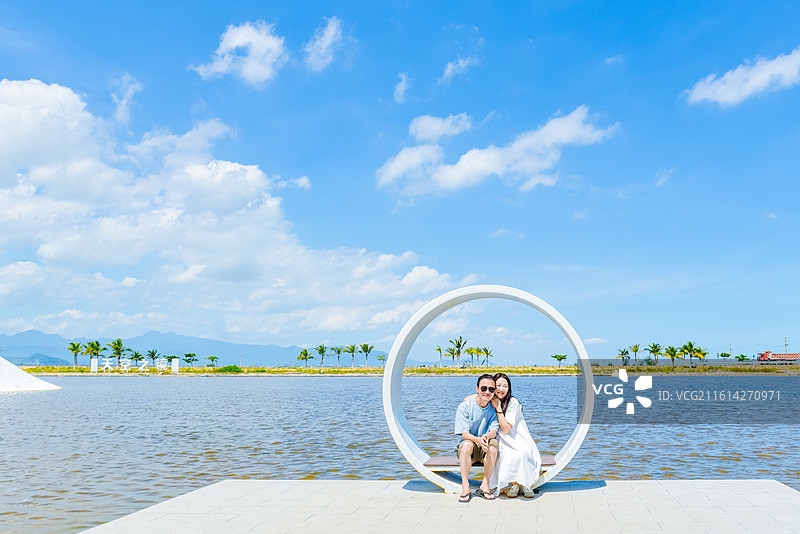 一对亚洲情侣在海南省乐东黎族自治县莺歌海盐场天空之镜享受盐田风景图片素材