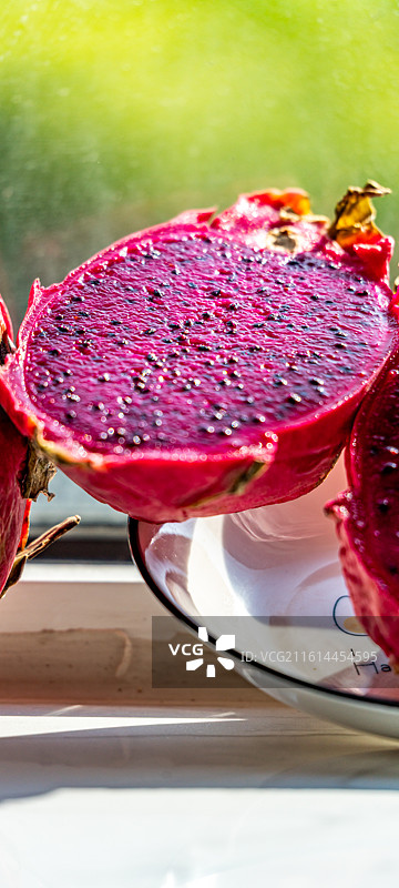 绿色虚化背景中桌上盘子里的火龙果水果果肉的特写镜头图片素材