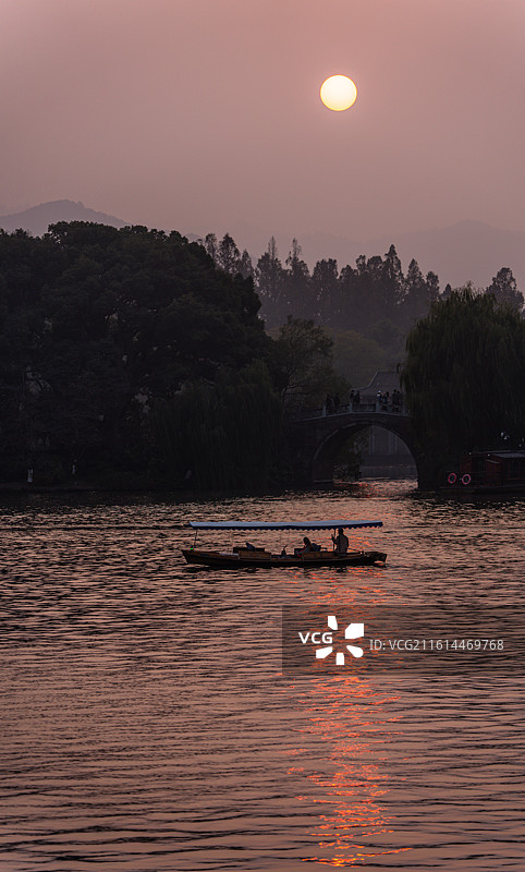 浙江杭州西湖孤山路口西泠桥看黄昏夕阳日落中的山水自然景观与游船图片素材