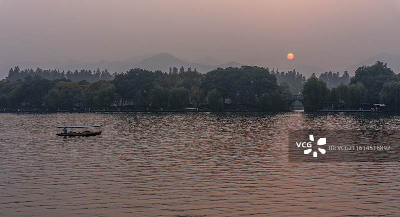 浙江杭州西湖孤山路口西泠桥看黄昏夕阳日落中的山水自然景观与游船图片素材