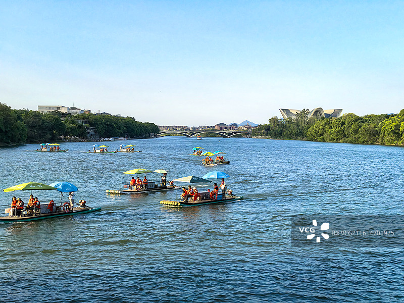 桂林漓江上竹筏游览的人们与远处的解放桥、漓江歌剧院图片素材