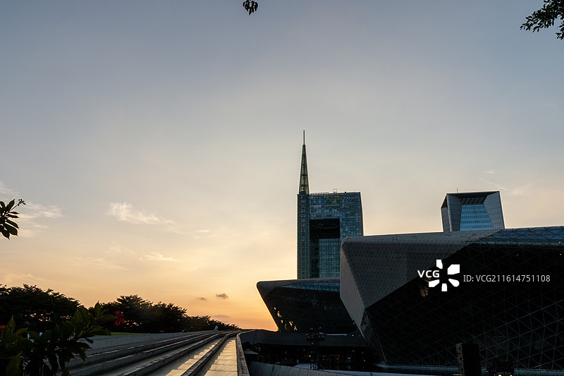 秋天日落时分橙色天空背景下的广州大剧院和城市摩天大楼建筑自然风光图片素材