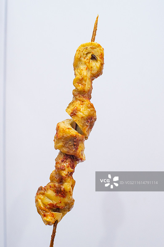中国饮食产业拍摄主题，瓷碗里放着一支金黄色刷着酱料的烤面筋零食小吃美食，室内无人图像摄影图片素材