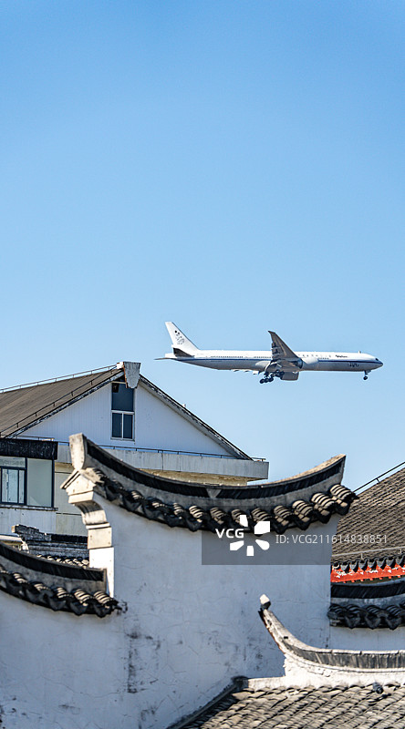 纯净蓝天下的上海闵行七宝老街古镇建筑上空掠过的民航飞机特写镜头图片素材