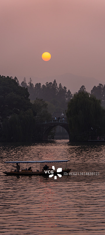 浙江杭州西湖孤山路口西泠桥看黄昏夕阳日落中的山水自然景观与游船图片素材