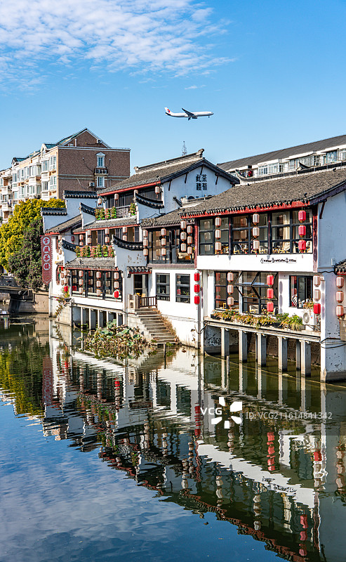 蓝天下的上海闵行七宝老街古镇建筑倒影景观与天空掠过的飞机特写镜头图片素材