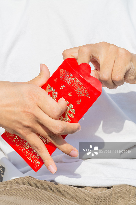 脑瘫患者拆开新春红包取出压岁钱现金，展示节日收获与喜悦瞬间。图片素材