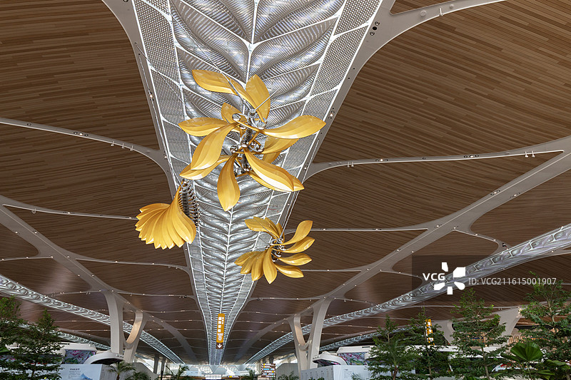 低视角下的广州白云机场T3航站楼天花板上悬挂的金色旋转叶片艺术装置图片素材