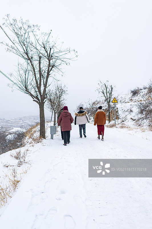 中国自然风光拍摄主题，几个人行走在冬天地面上的厚厚的白雪和一对脚印，户外白昼人图像摄影图片素材