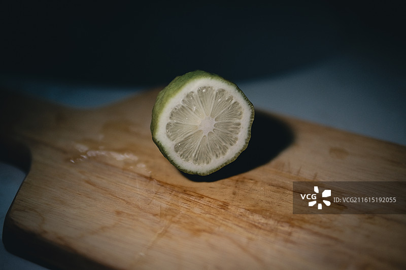 木质砧板上切开的青柠特写与暗调光影【Close-up of Sliced Lime on Woode图片素材