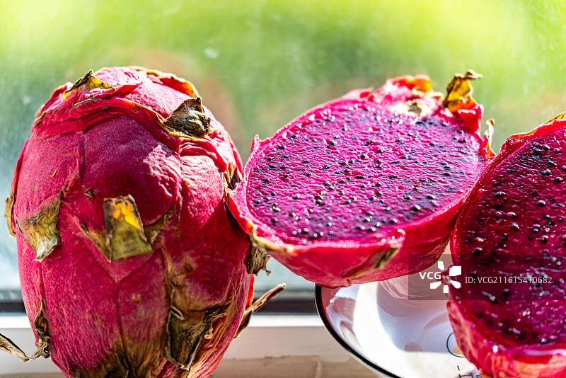 绿色虚化背景中桌上盘子里的火龙果水果果肉的特写镜头图片素材