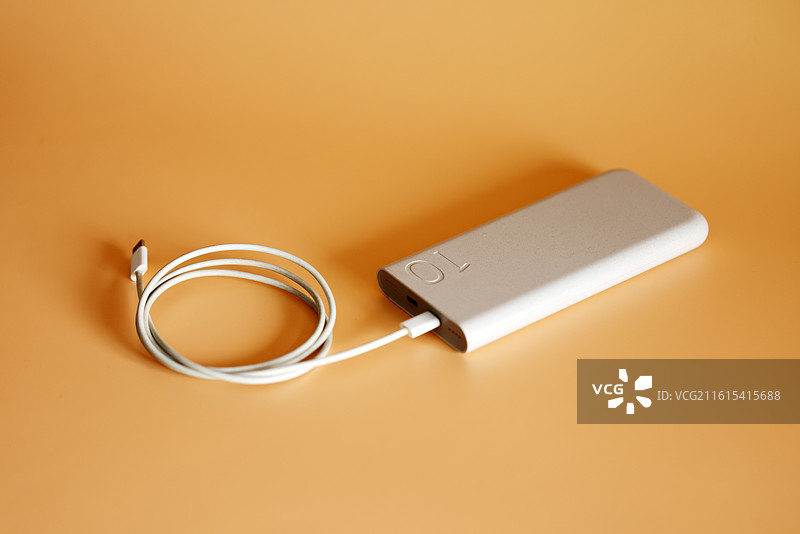 橙色背景下的智能手机和移动电源充电宝数据线特写镜头图片素材