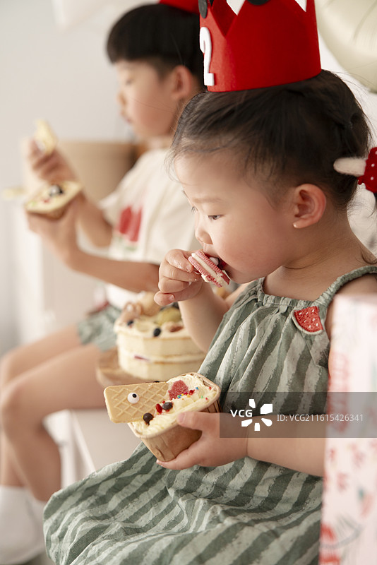 两岁小女孩乐滋滋地吃生日蛋糕场景图片素材